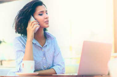 Kahve dükkanında çalışırken telefonu kullanarak iş kadını