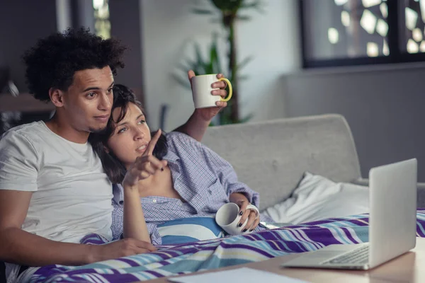 Jovem casal assistindo um filme em seu laptop na cama — Fotografia de Stock