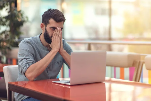 Ritratto di mezza lunghezza del designer barbuto di successo che sorride alla fotocamera mentre lavora come freelance su netbook . — Foto Stock