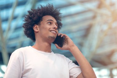 Genç adam uzakta üstünde hareket eden telefon kafede konuşurken arıyorsunuz