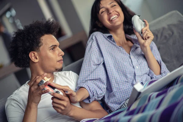 Imagen de pareja joven y cariñosa en la cocina en casa en interiores. Comer pizza y jugar con la consola . — Foto de Stock