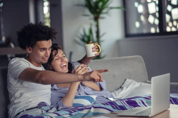 Young couple watching a movie on their laptop in bed