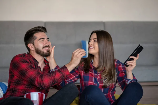 Casal lutando por controle remoto enquanto assiste TV em casa — Fotografia de Stock