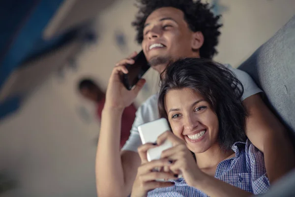 Attraktivt par som sitter på soffan tillsammans titta på smartphone hemma i vardagsrummet — Stockfoto