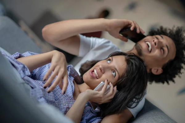 Attraktivt par som sitter på soffan tillsammans titta på smartphone hemma i vardagsrummet — Stockfoto