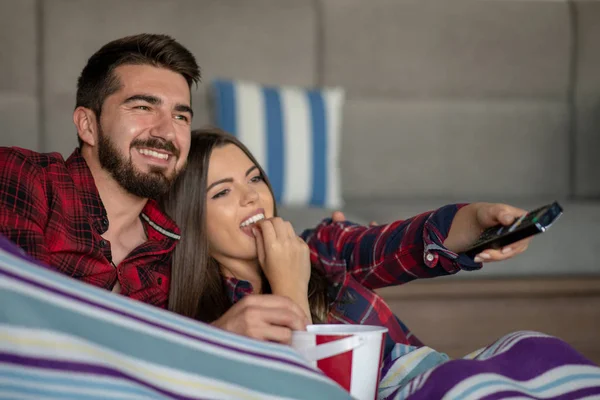 Pareja enamorada disfrutando de su tiempo libre, sentada en un sofá junto a la ventana, jugando videojuegos y divirtiéndose . — Foto de Stock