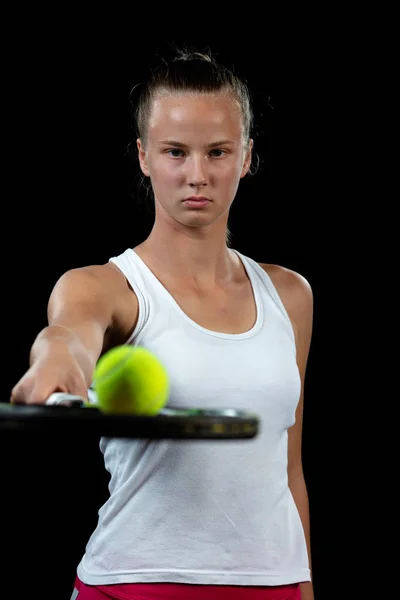 Una joven practicando tenis. Jugador principiante sosteniendo una raqueta, aprendiendo habilidades básicas. Retrato sobre fondo negro . — Foto de Stock