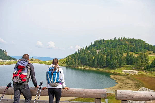 Casal jovem de mochileiros perto do lago em montanhas — Fotografia de Stock