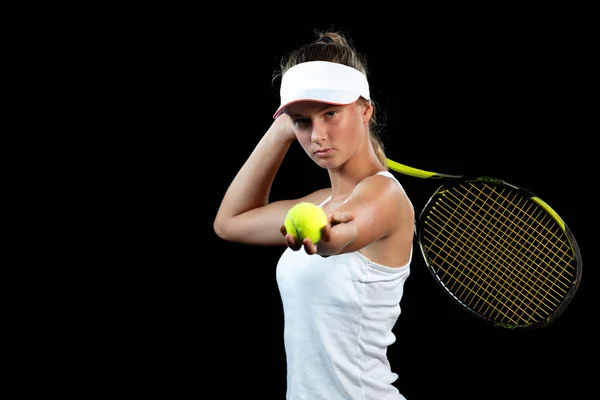 Νεαρή γυναίκα σε μια πρακτική τένις. Αρχάριος παίκτης που κρατάει μια ρακέτα, εκμάθηση βασικών δεξιοτήτων. Πορτραίτο σε μαύρο φόντο. — Φωτογραφία Αρχείου