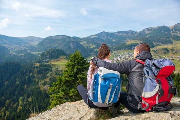 Dos excursionistas en el mirador en las montañas disfrutando de una hermosa vista del valle con un lago . — Foto de Stock