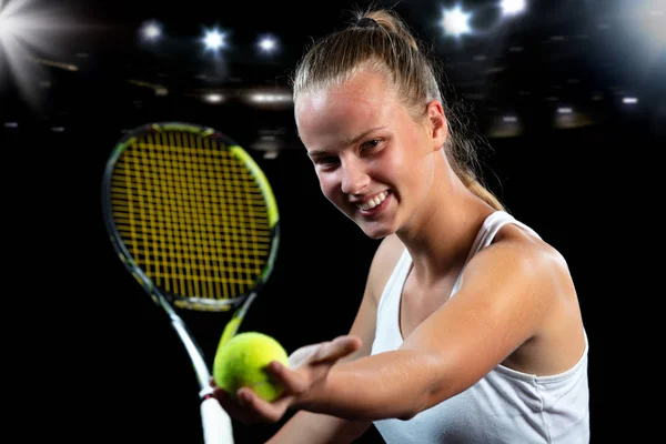 Ung kvinna på en tennis praxis. Nybörjare spelare håller en racket, lära sig grundläggande färdigheter. Porträtt på svart bakgrund. — Stockfoto