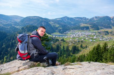 Genç erkek uzun yürüyüşe çıkan kimse sırt çantası rahatlatıcı sakin yaz gün boyunca bir dağın tepesinde ile.