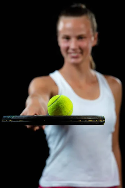 Una joven practicando tenis. Jugador principiante sosteniendo una raqueta, aprendiendo habilidades básicas. Retrato sobre fondo negro . — Foto de Stock