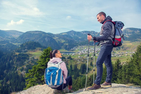 Två vandrare på viewpoint i bergen njuter av vacker utsikt över dalen med en sjö. — Stockfoto
