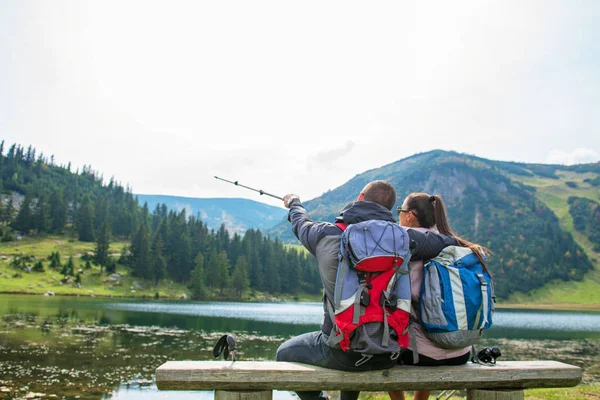 Fiatal pár backpackers a tó, a hegyek közelében — Stock Fotó