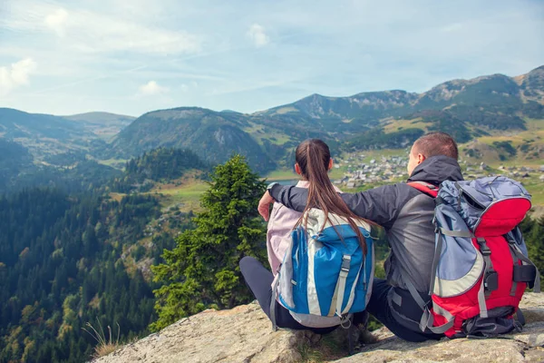 Two hikers at viewpoint in the mountains enjoying beautiful view of the valley with a lake. — Stock Photo, Image