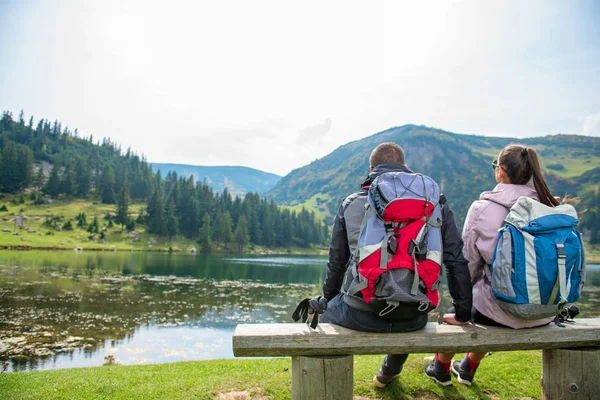 Unga par backpackers nära sjön i bergen — Stockfoto