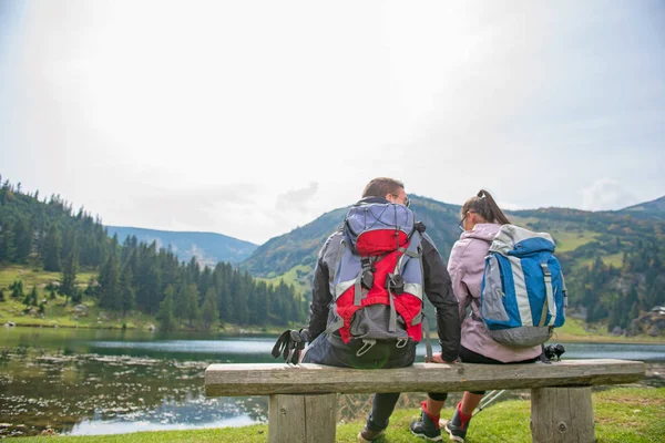 Pareja joven de mochileros cerca del lago en las montañas — Foto de Stock