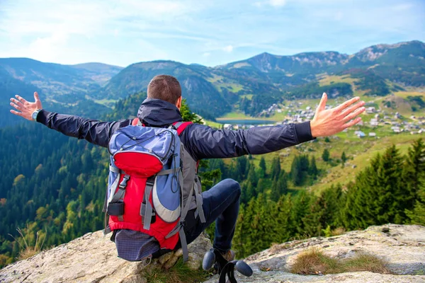 Joven excursionista masculino con mochila relajándose en la cima de una montaña durante el tranquilo día de verano . — Foto de Stock
