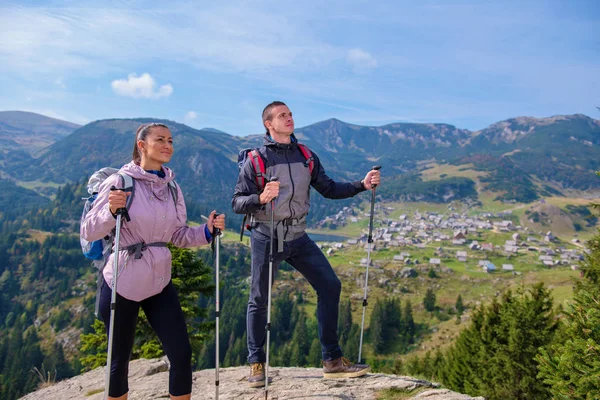 Senderistas con mochilas relajándose en la cima de una montaña y disfrutando de la vista del valle — Foto de Stock