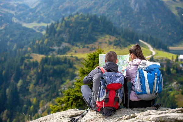 Lächelndes Abenteuerpaar mit Landkarte am Hang. Blick auf die Karte — Stockfoto