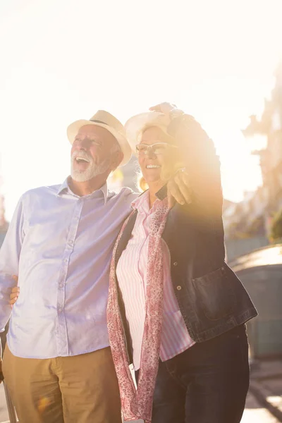 Feliz alegre pareja de turistas mayores con mapa y guía de la ciudad caminando por la calle —  Fotos de Stock