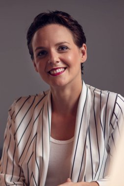 Genç gülümseyen iş kadını portre gri arka plan üzerinde.