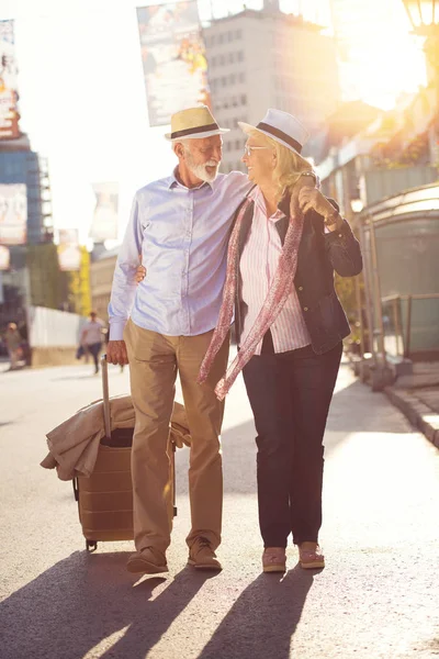 Feliz casal idoso alegre de turistas com mapa e guia da cidade andando na rua — Fotografia de Stock