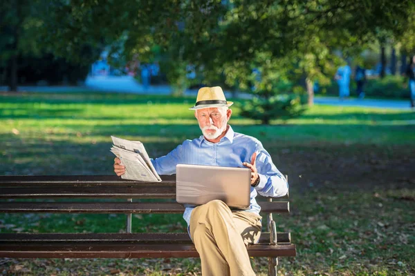 Homem sênior usando computador portátil em repouso no parque ao ar livre — Fotografia de Stock