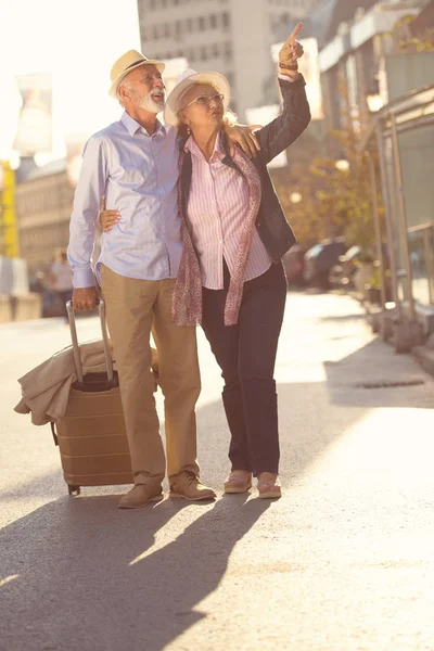 Feliz alegre pareja de turistas mayores con mapa y guía de la ciudad caminando por la calle —  Fotos de Stock