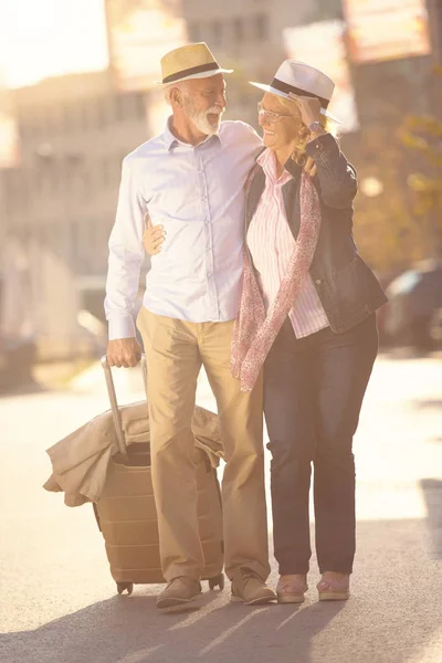 Feliz alegre pareja de turistas mayores con mapa y guía de la ciudad caminando por la calle —  Fotos de Stock