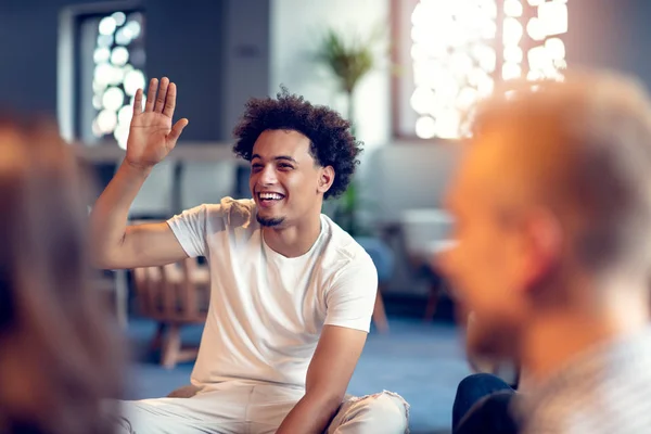 Diverse people in startup business meeting raising hand