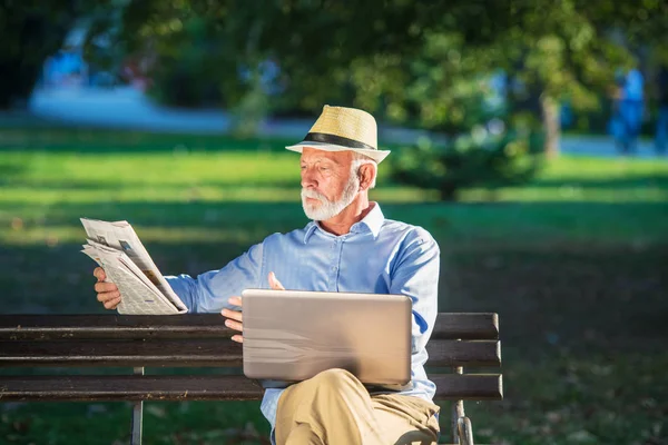 Homem sênior usando computador portátil em repouso no parque ao ar livre — Fotografia de Stock