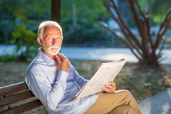 Retrato de un hombre mayor leyendo periódicos en el parque . — Foto de Stock