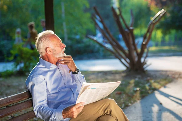 Retrato de un hombre mayor leyendo periódicos en el parque . —  Fotos de Stock
