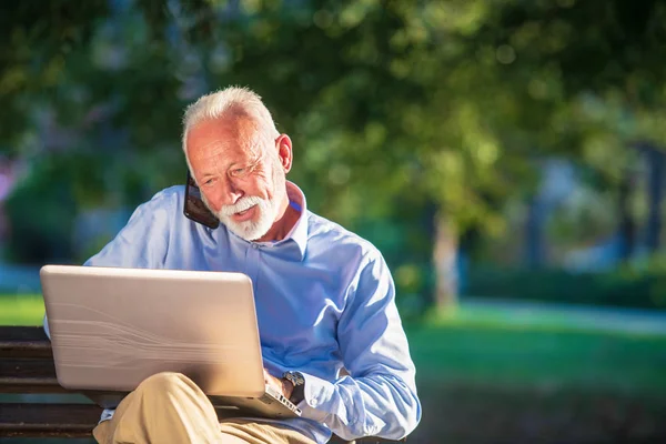 Correspondência comercial. Focado homem de negócios maduro usando laptop enquanto sentado no parque — Fotografia de Stock