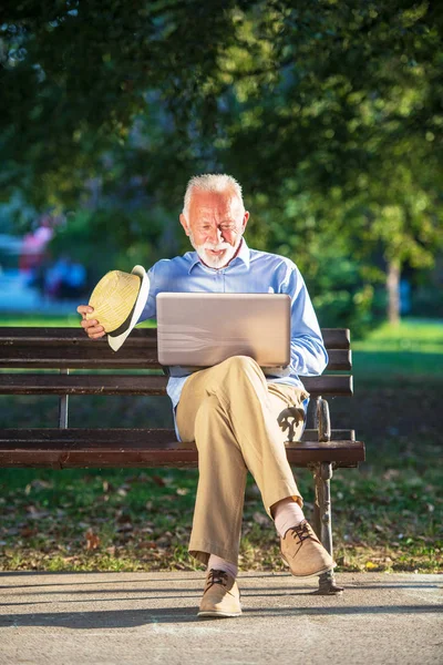 Starší muž používat přenosný počítač v klidu v parku venku — Stock fotografie