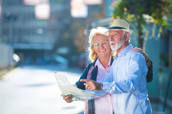 Старша пара туристів, які дивляться на карту міста — стокове фото