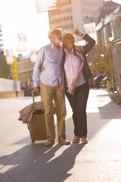 Feliz alegre pareja de turistas mayores con mapa y guía de la ciudad caminando por la calle —  Fotos de Stock