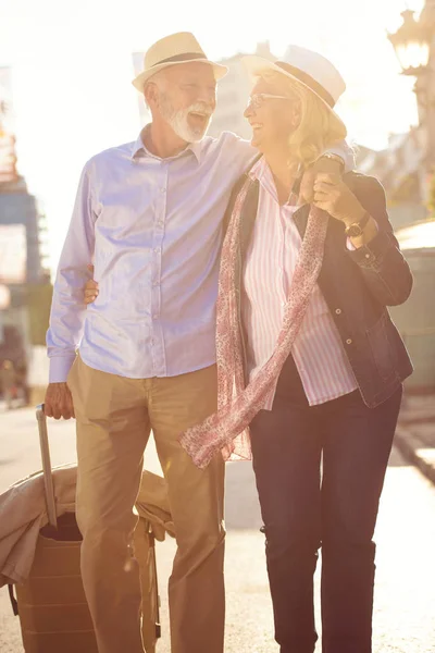 Feliz alegre pareja de turistas mayores con mapa y guía de la ciudad caminando por la calle —  Fotos de Stock