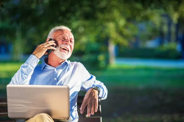 Business correspondence. Focused mature businessman using laptop while sitting in park