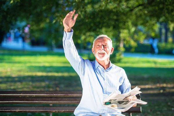 Hombre mayor relajándose en el parque en un día soleado sentado en un banco de madera y esperando a alguien — Foto de Stock