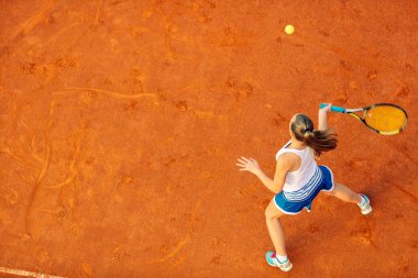 Maç sırasında sahada bir kadın tenisçi havadan çekilmiş. Tenis oynayan genç bir kadın. Yüksek açı görünümü.