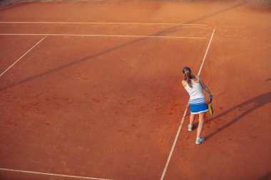 Sportif kıyafeti ve sağlıklı bir yaşam tarzı ile toprak kortta Tenis oynayan kadın