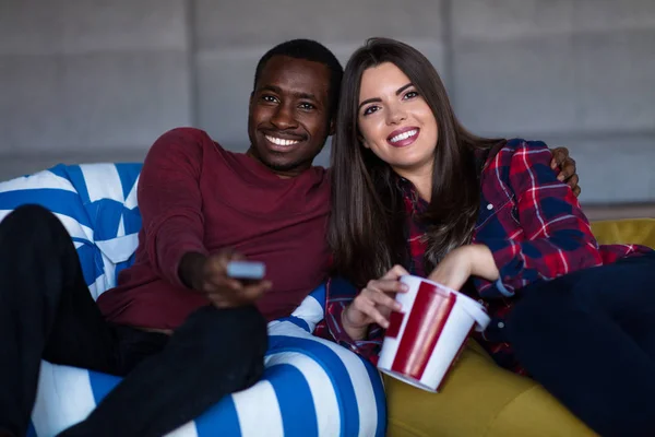 Portrét mladého páru sedícího na pohovce a pozoruje film s výrazem na tvářích — Stock fotografie
