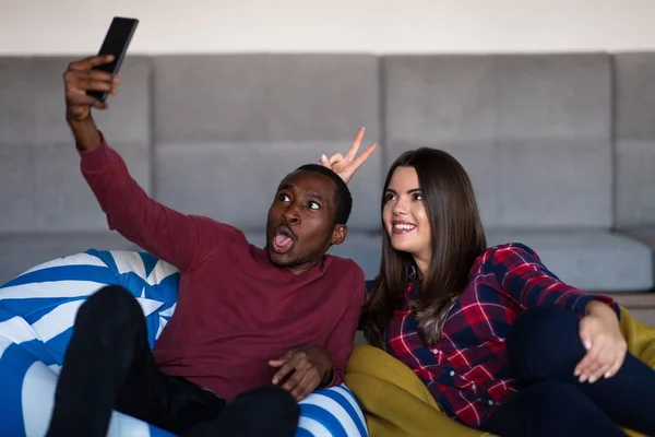 Pareja feliz con la tableta de ordenador y teléfono inteligente en un sofá — Foto de Stock