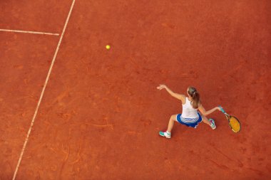 Maç sırasında sahada bir kadın tenisçi havadan çekilmiş. Tenis oynayan genç bir kadın. Yüksek açı görünümü.