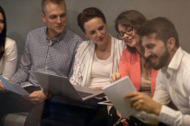 Modern ofis çok ırklı genç yaratıcı insanlar. Grup Genç iş adamları dizüstü bilgisayar, tablet, akıllı telefon, Not defteri ile birlikte çalışıyoruz.