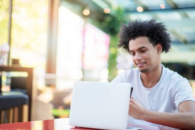 Parlak oturma odasında otururken diz üstü görünen galip yakışıklı adam