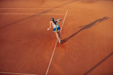 Sportif kıyafeti ve sağlıklı bir yaşam tarzı ile toprak kortta Tenis oynayan kadın